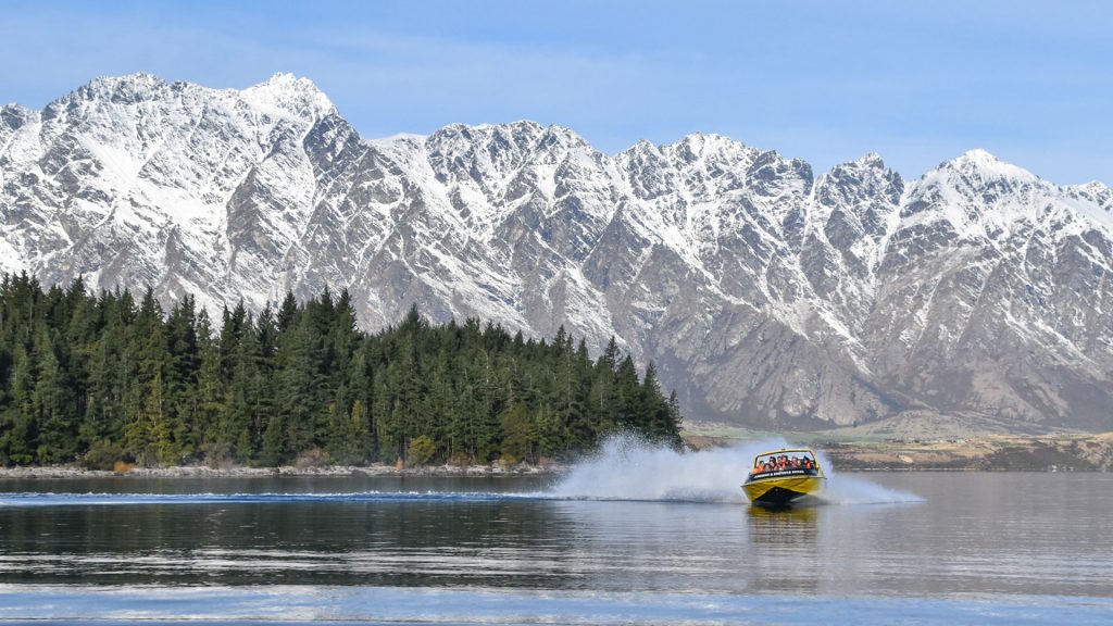 KJet Queenstown jet boating on lake wakatipu in winter with snow on the remarkables water spash behind boat